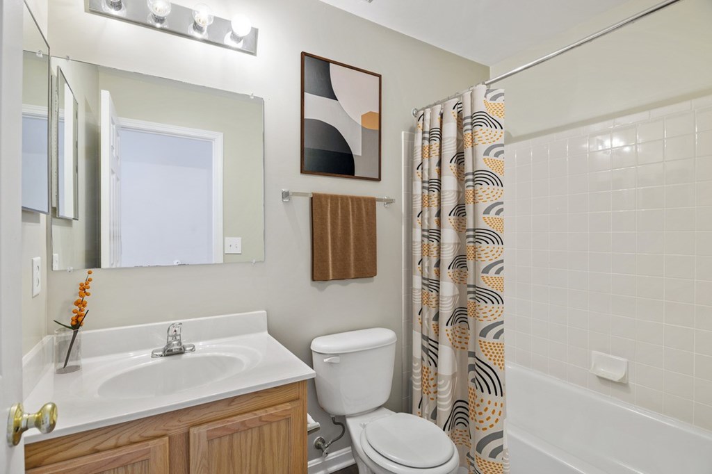 A bathroom with a white sink, toilet, and shower curtain.